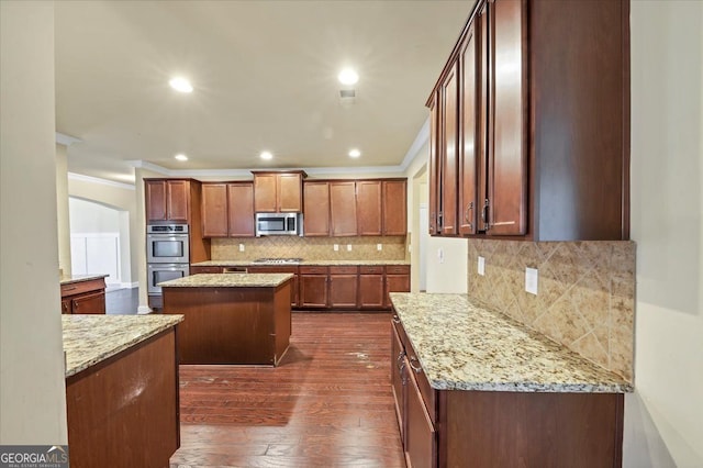 kitchen featuring light stone counters, stainless steel appliances, dark wood-type flooring, and a center island