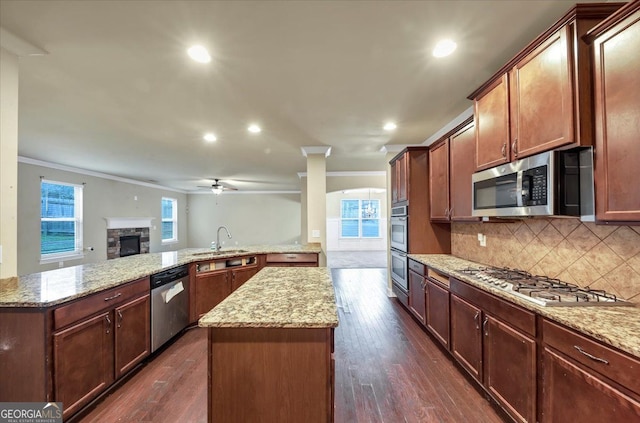 kitchen with sink, dark hardwood / wood-style floors, crown molding, a kitchen island, and appliances with stainless steel finishes