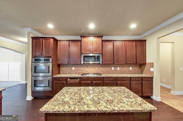 kitchen with stainless steel appliances, dark hardwood / wood-style floors, light stone counters, and crown molding