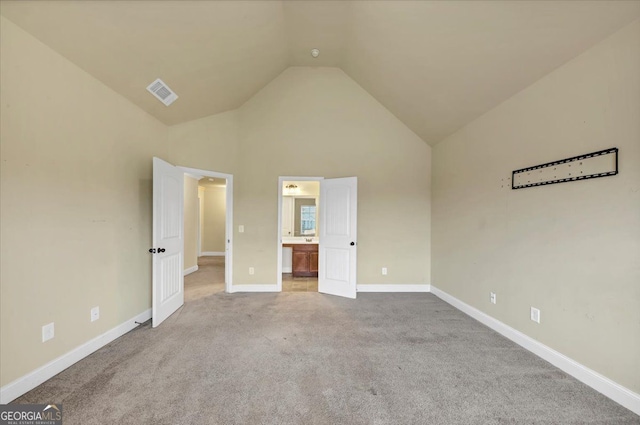 unfurnished bedroom featuring connected bathroom, high vaulted ceiling, and carpet