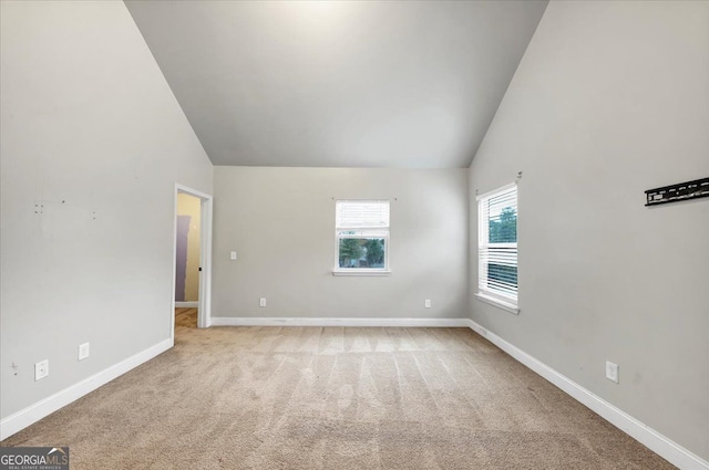 spare room with light colored carpet and lofted ceiling