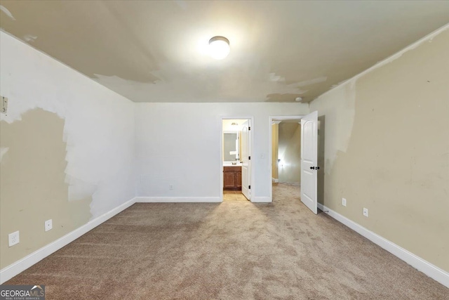 unfurnished bedroom featuring light carpet and ensuite bath