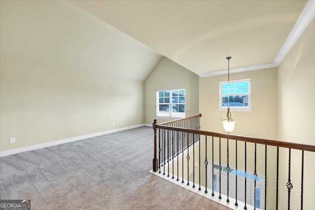 hall with lofted ceiling, an inviting chandelier, carpet flooring, and ornamental molding