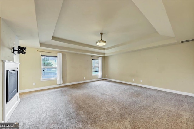 unfurnished living room with carpet and a tray ceiling