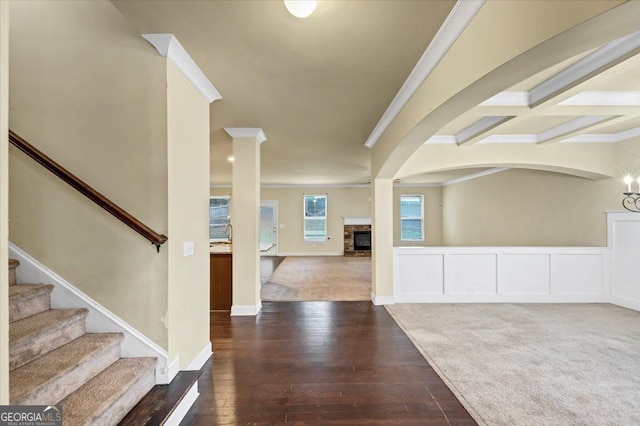 entrance foyer featuring beam ceiling, dark colored carpet, crown molding, and decorative columns