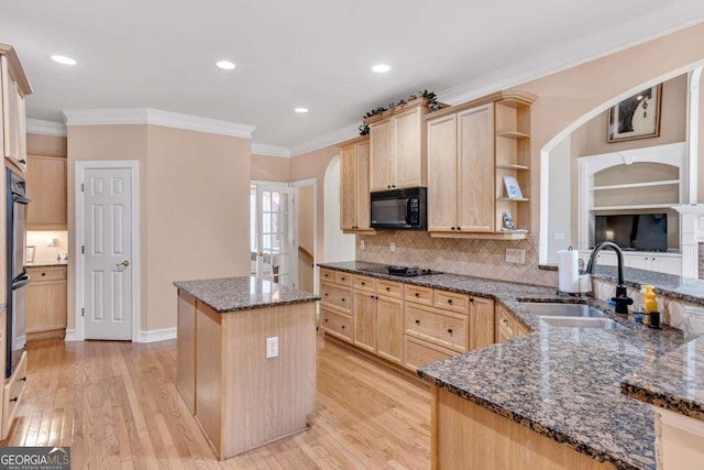 kitchen with sink, black appliances, light brown cabinetry, dark stone countertops, and light wood-type flooring