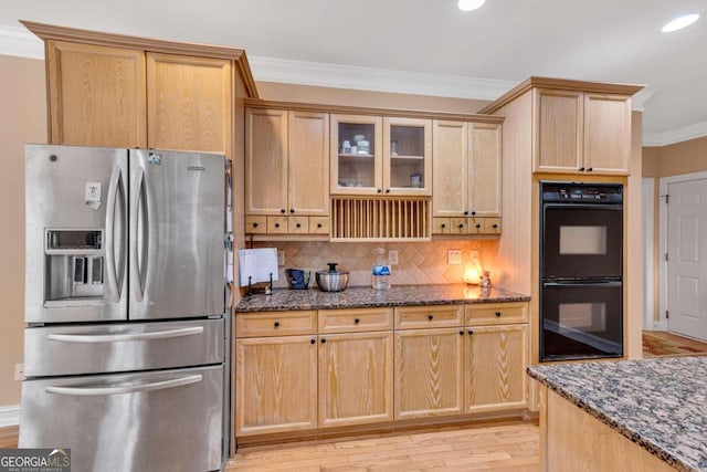 kitchen featuring crown molding, black double oven, stainless steel refrigerator with ice dispenser, light hardwood / wood-style floors, and dark stone countertops