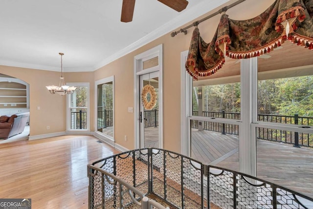 interior space with built in shelves, light hardwood / wood-style floors, ceiling fan with notable chandelier, and crown molding