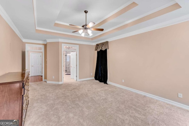 spare room with ceiling fan, a tray ceiling, light carpet, and ornamental molding