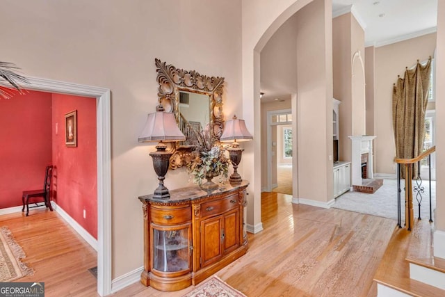 foyer entrance with a fireplace, light hardwood / wood-style flooring, and crown molding