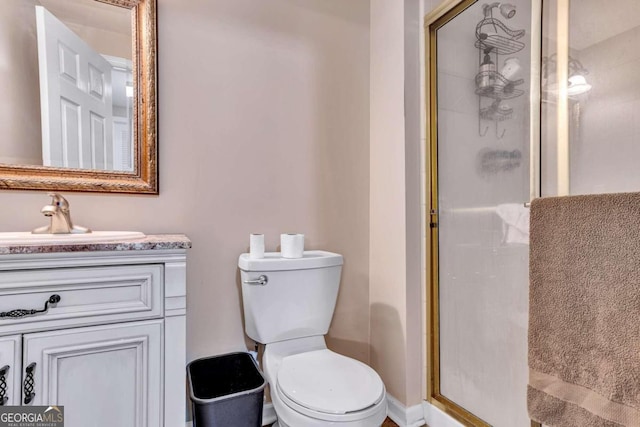 bathroom featuring a shower with door, vanity, and toilet