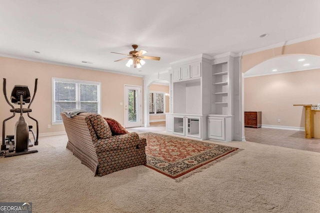 living room featuring ceiling fan, light carpet, and crown molding