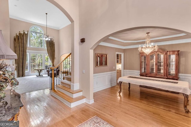 foyer entrance featuring ornamental molding, light wood-type flooring, a chandelier, and a tray ceiling