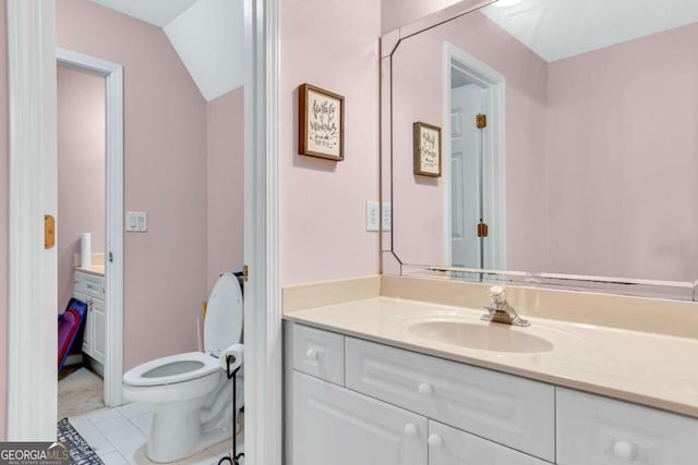 bathroom with tile patterned flooring, vanity, toilet, and vaulted ceiling