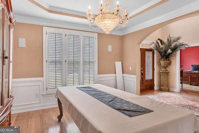 bedroom featuring a raised ceiling, crown molding, and light hardwood / wood-style flooring