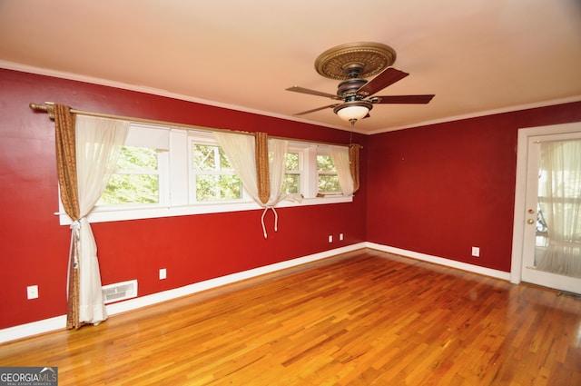 unfurnished room featuring wood-type flooring, ornamental molding, plenty of natural light, and ceiling fan