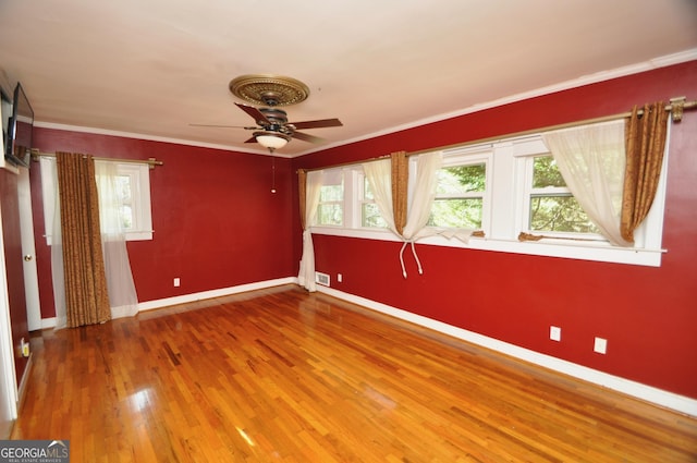 spare room featuring ornamental molding, wood-type flooring, and plenty of natural light