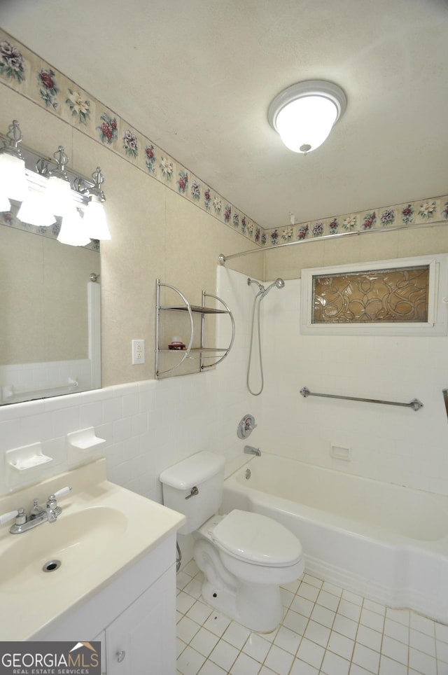 full bathroom with tile walls, toilet, tile patterned floors, vanity, and tiled shower / bath combo