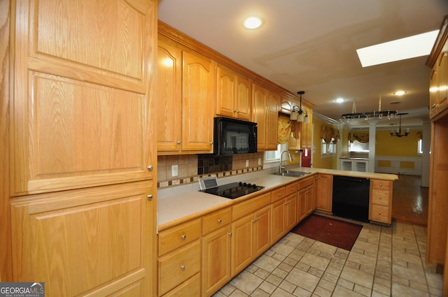 kitchen with hanging light fixtures, black appliances, tasteful backsplash, a skylight, and sink