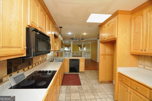 kitchen featuring sink, decorative backsplash, a skylight, hanging light fixtures, and black appliances