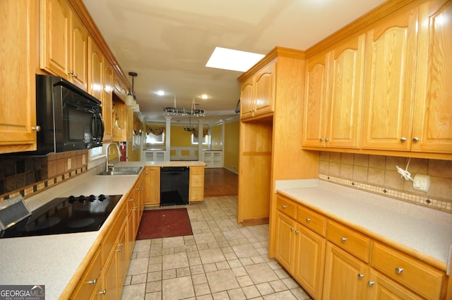 kitchen featuring pendant lighting, black appliances, a skylight, backsplash, and sink