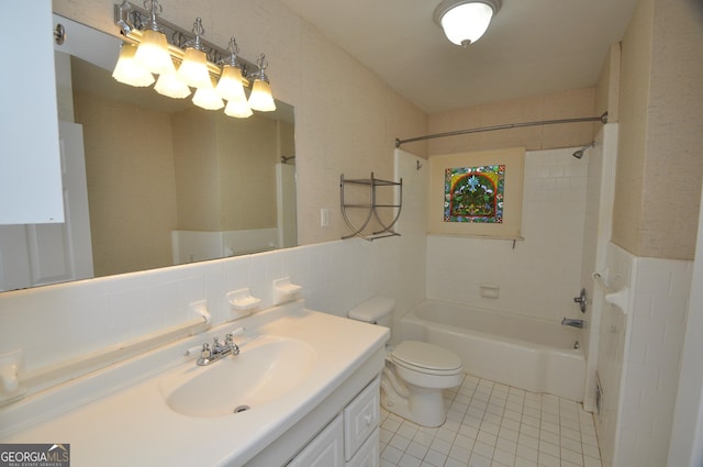 full bathroom with tile patterned flooring, tile walls, toilet, vanity, and tiled shower / bath combo