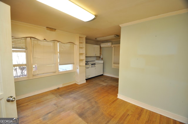 empty room featuring hardwood / wood-style flooring, ornamental molding, and a wall mounted air conditioner