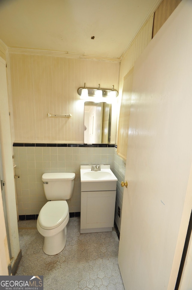 bathroom with tile walls, toilet, ornamental molding, and vanity