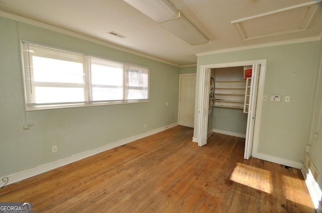 unfurnished bedroom with hardwood / wood-style floors, a closet, and crown molding