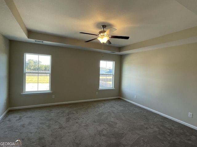 carpeted empty room featuring ceiling fan and a raised ceiling