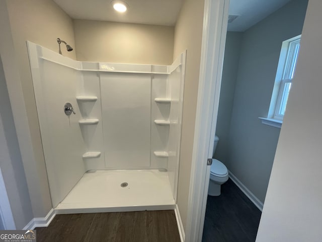 bathroom featuring a shower, hardwood / wood-style flooring, and toilet