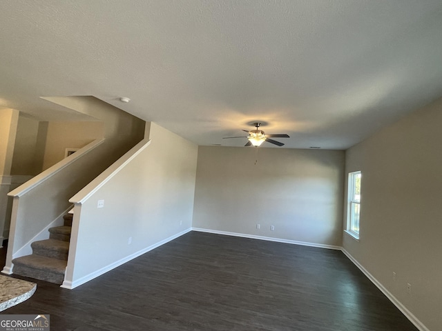 unfurnished living room featuring a textured ceiling, ceiling fan, and dark wood-type flooring