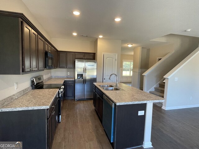 kitchen featuring a kitchen island with sink, sink, dark hardwood / wood-style floors, dark brown cabinets, and stainless steel appliances