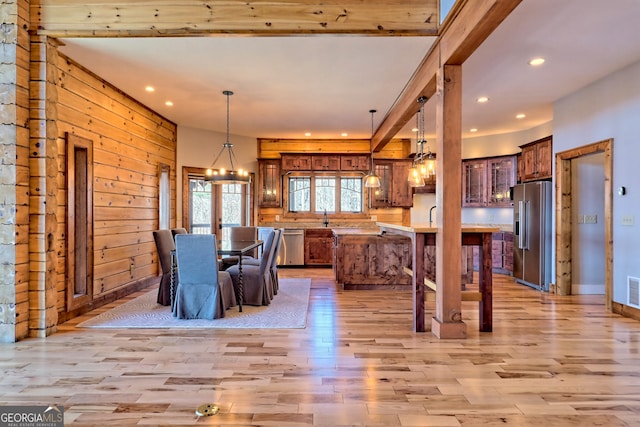 unfurnished dining area featuring wood walls, a chandelier, sink, and light wood-type flooring