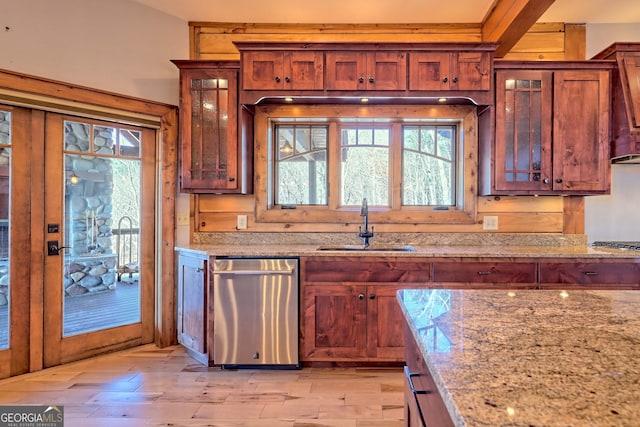 kitchen featuring stainless steel dishwasher, sink, light stone counters, and light hardwood / wood-style flooring