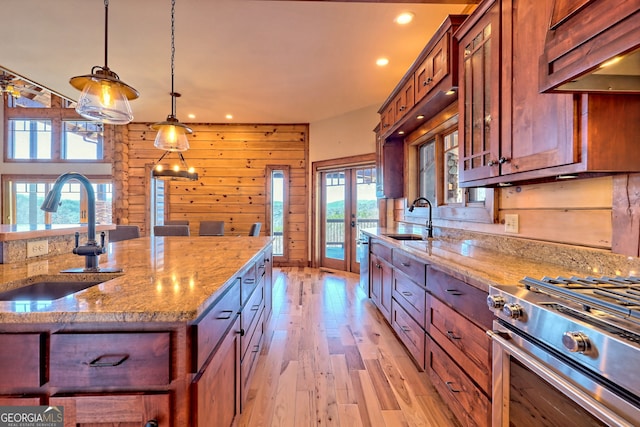 kitchen featuring appliances with stainless steel finishes, light hardwood / wood-style flooring, sink, and light stone counters