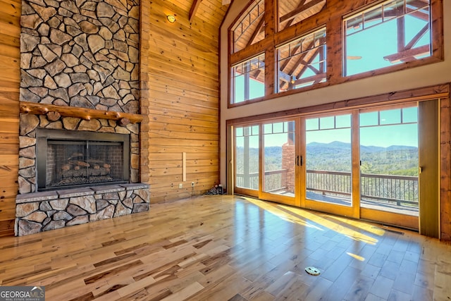 unfurnished living room with a mountain view, high vaulted ceiling, wood-type flooring, and a healthy amount of sunlight