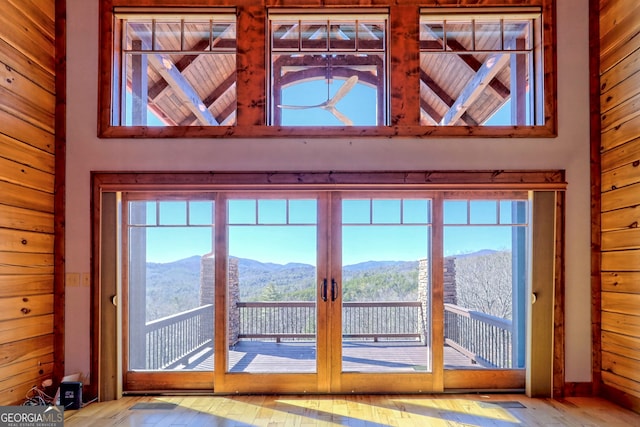 doorway to outside featuring wooden walls, a mountain view, and a healthy amount of sunlight