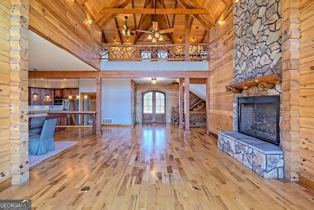 unfurnished living room with high vaulted ceiling, light hardwood / wood-style floors, a fireplace, and wooden ceiling