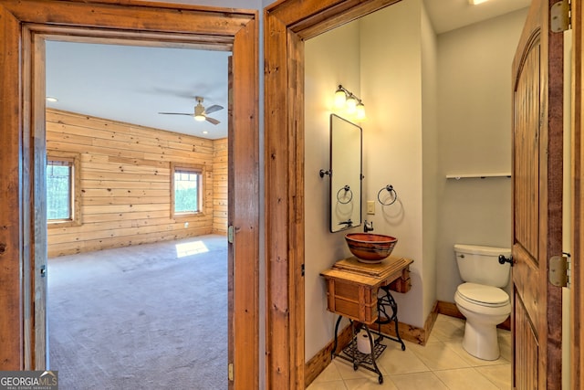 bathroom featuring wood walls, ceiling fan, tile patterned flooring, and toilet