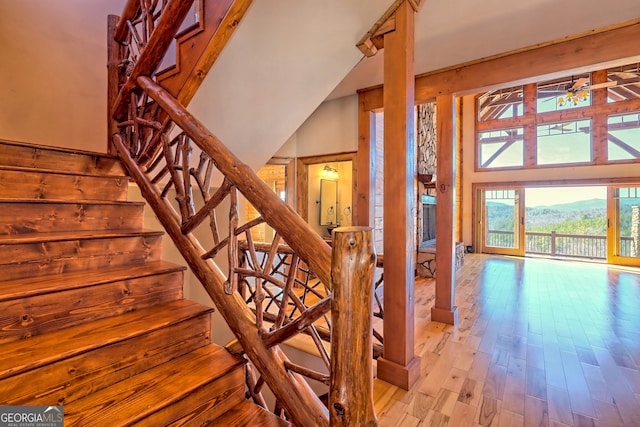 stairway with wood-type flooring, a mountain view, ceiling fan, and a towering ceiling