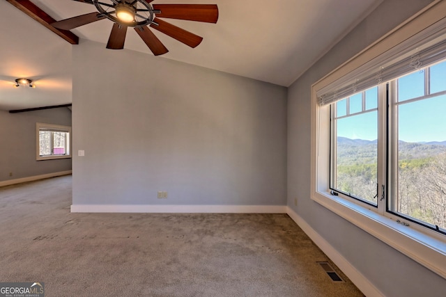 carpeted empty room with lofted ceiling with beams, a mountain view, and ceiling fan