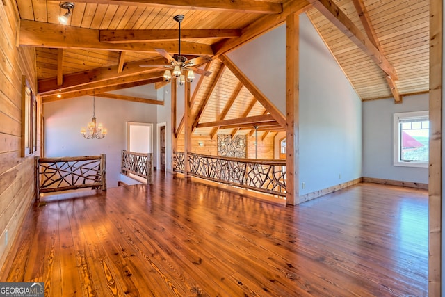 interior space with hardwood / wood-style floors, wood walls, and beam ceiling