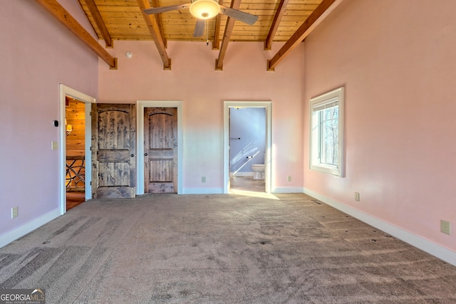 unfurnished bedroom featuring wood ceiling, carpet floors, ensuite bathroom, beam ceiling, and a high ceiling