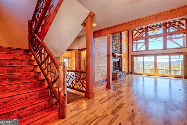 interior space featuring a towering ceiling, hardwood / wood-style floors, wooden walls, ceiling fan, and a fireplace