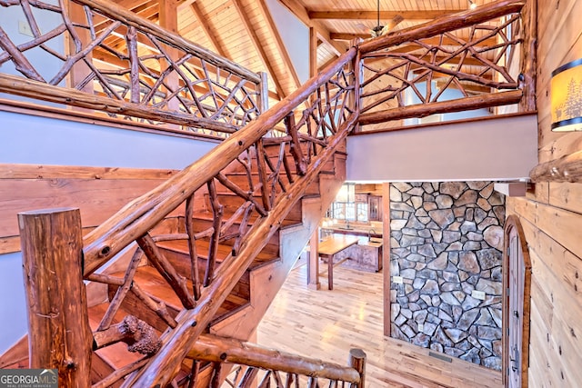 stairs with wood walls, hardwood / wood-style floors, wood ceiling, and beam ceiling