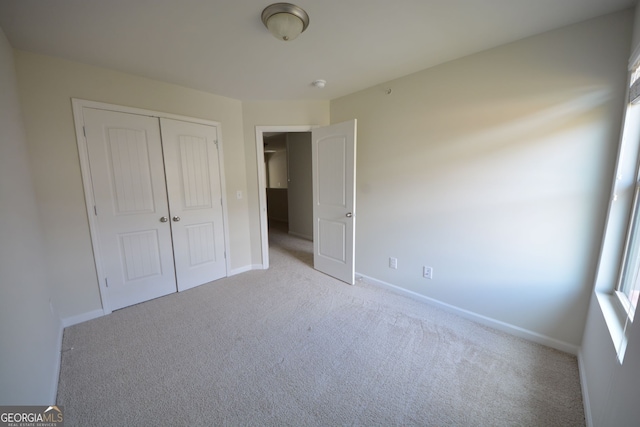 unfurnished bedroom with a closet and light colored carpet