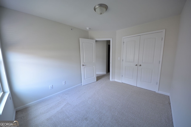 unfurnished bedroom with light carpet and a closet