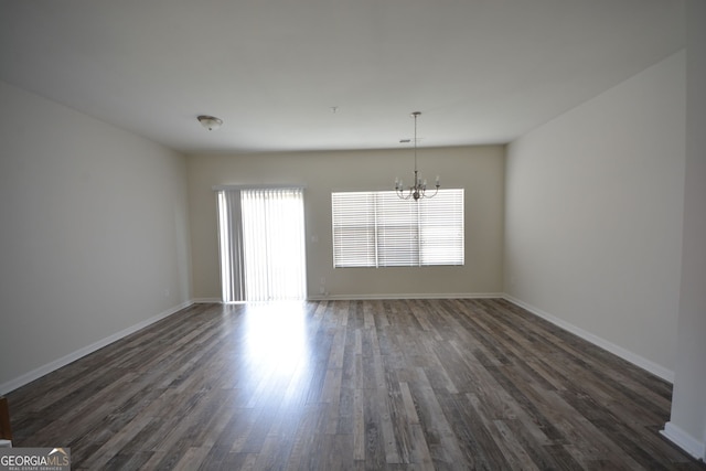 empty room featuring a chandelier and dark hardwood / wood-style flooring