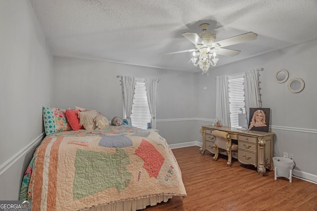 bedroom featuring light wood-type flooring, a textured ceiling, and ceiling fan